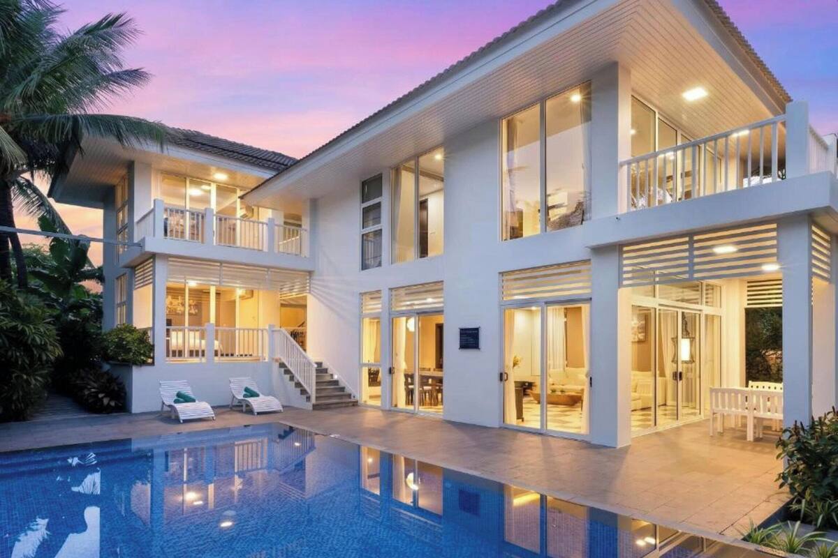 A modern multi-story house with a swimming pool, balconies, and a covered outdoor area.