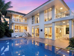 Ein modernes mehrgeschossiges Haus mit Swimmingpool, Balkonen und einer überdachten Terrasse.