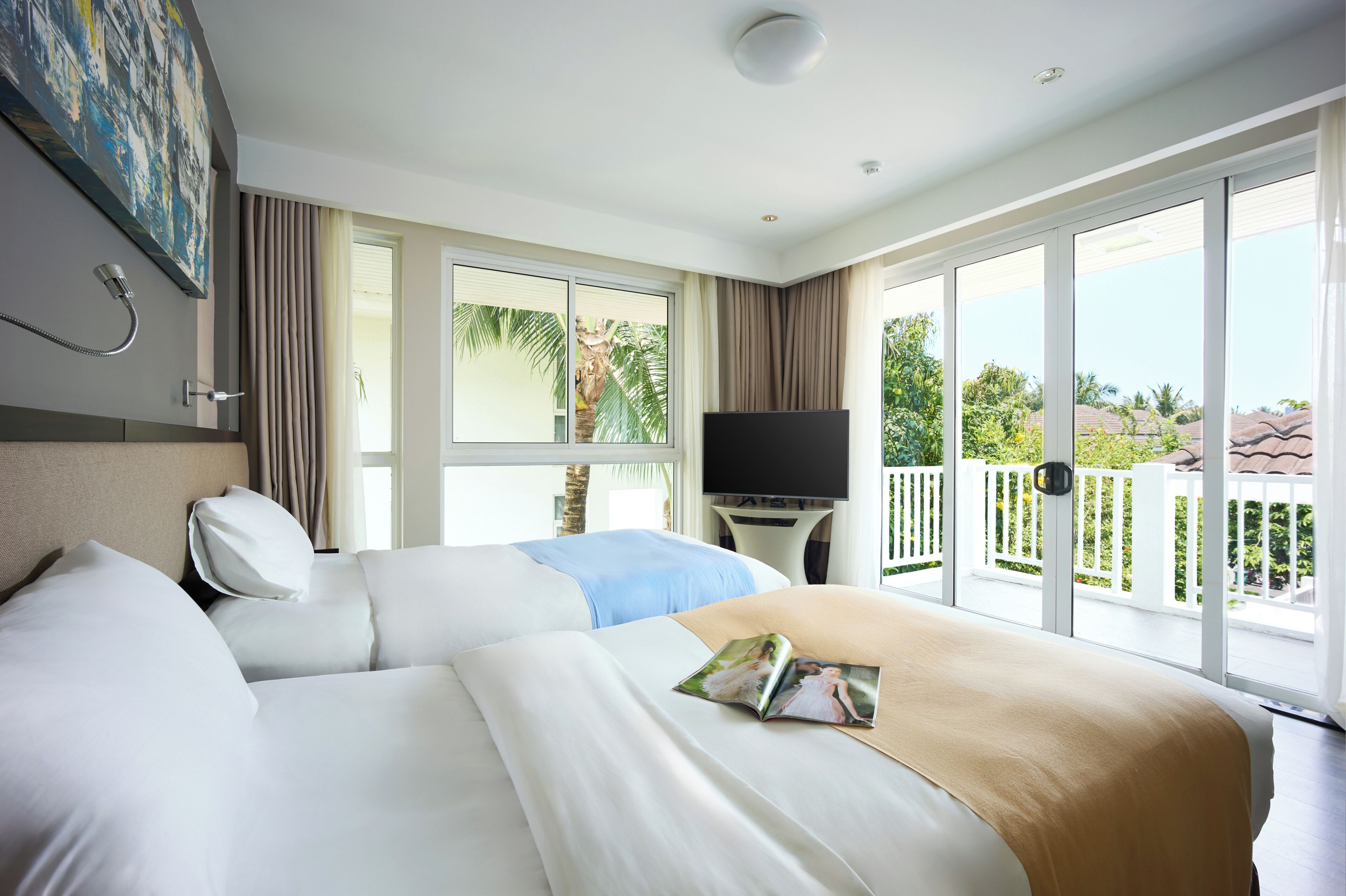 Habitación de hotel con dos camas, un televisor de pantalla plana, un balcón con barandilla blanca y vistas a palmeras.