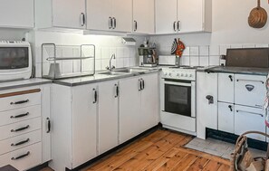 A kitchen with white cabinets, a stove, a microwave, and a sink. - 3 bedroom cozy home in Slite (Slite)