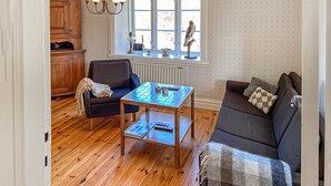 Un salon chaleureux avec un plancher en bois, un canapé bleu, une petite table et une fenêtre donnant sur un beau paysage.