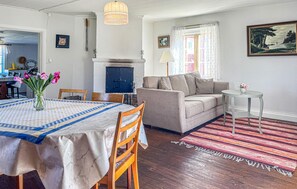 A living room with a sofa, a dining table with a vase of flowers, and a fireplace. - Amazing home in Motala with ethernet internet (Motala)
