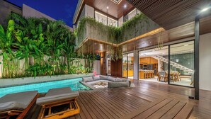 Ein modernes Haus mit einer Holterrasse, einem Schwimmbecken und einem Essbereich.