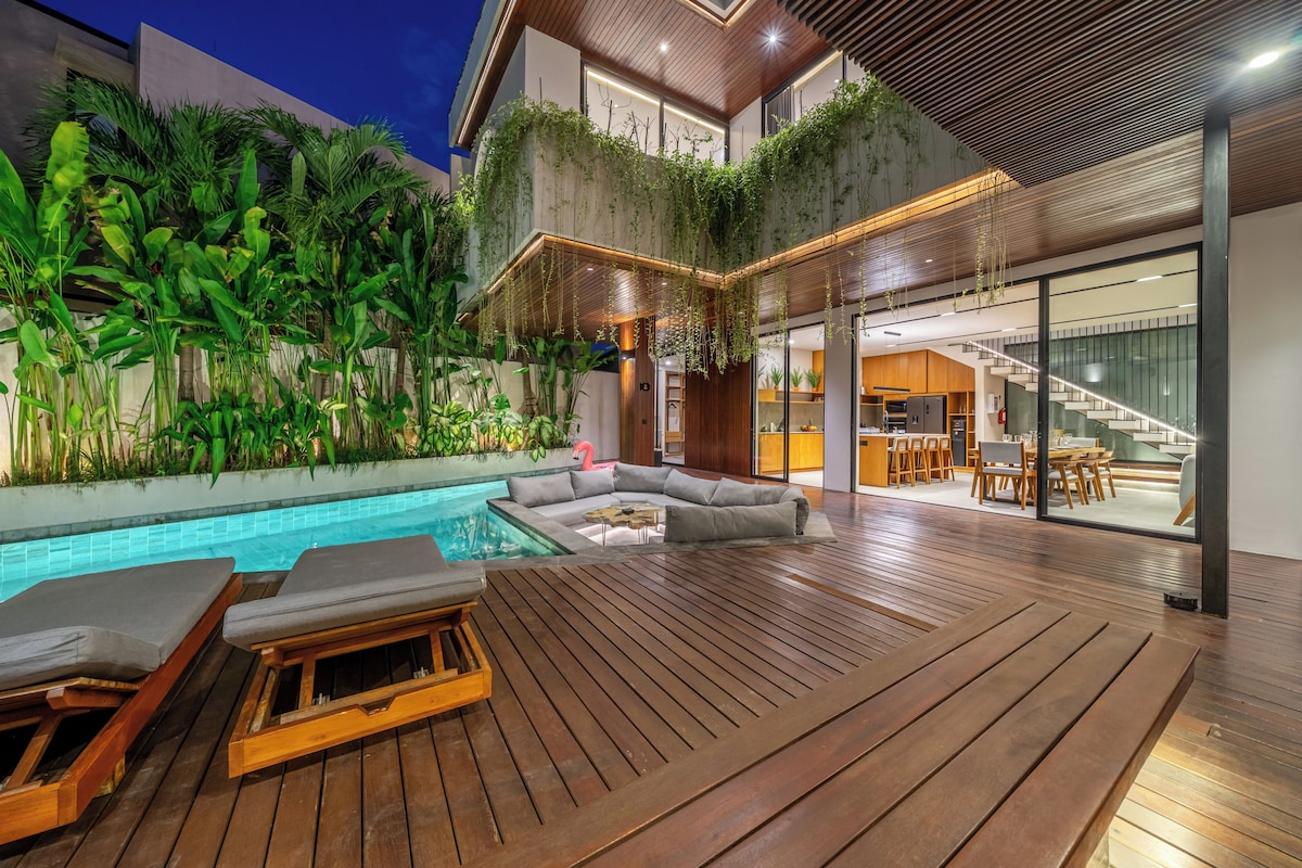 Ein modernes Haus mit einer Holterrasse, einem Schwimmbecken und einem Essbereich.