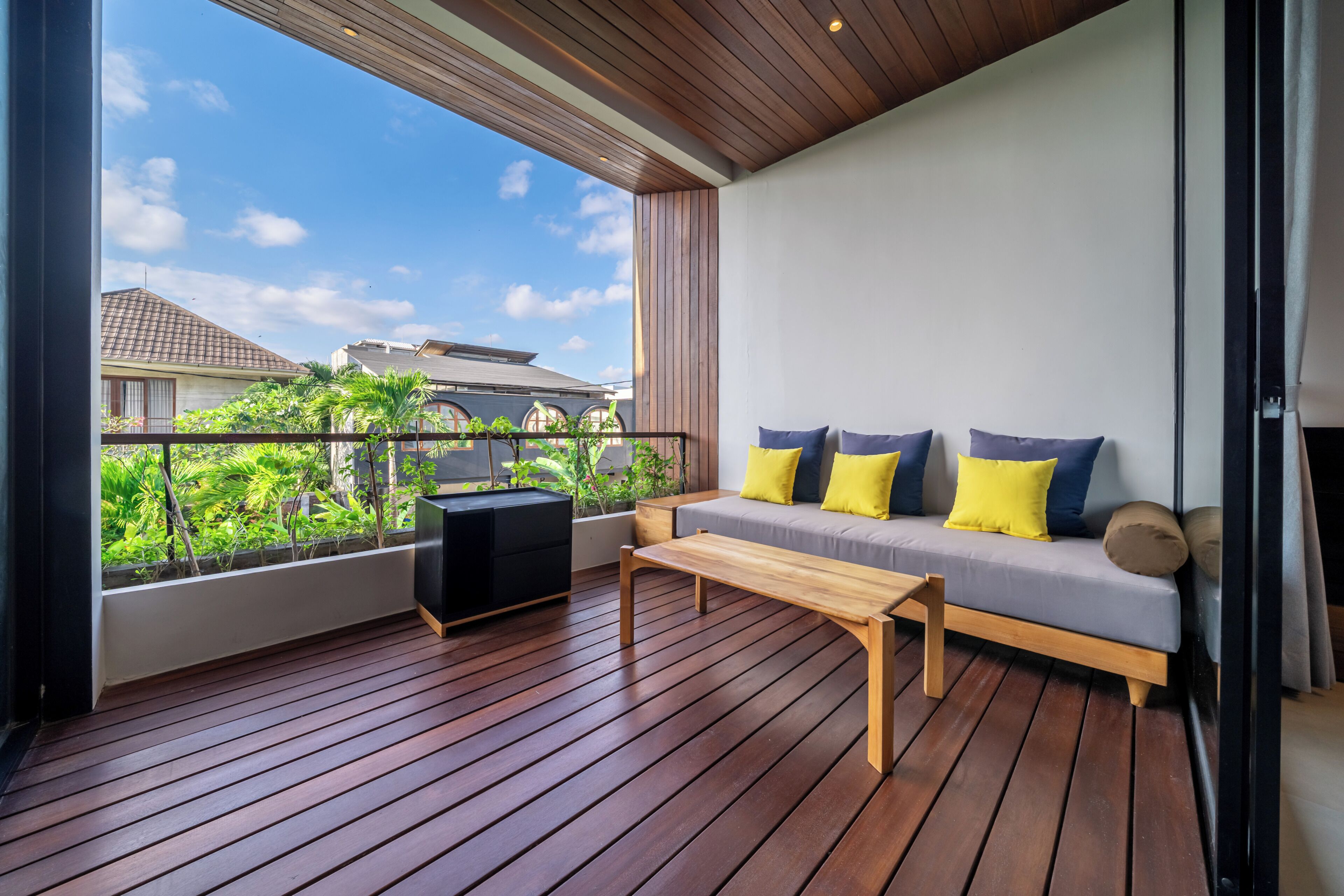 Un balcon avec un plancher en bois, un canapé avec des coussins et une petite table.