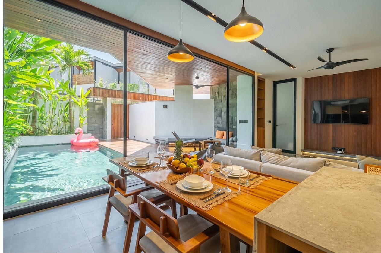 Un soggiorno moderno con zona pranzo, piscina e televisore.