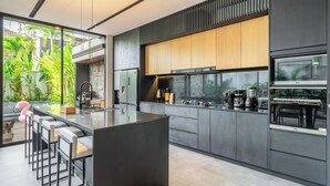 Eine moderne Küche mit einer zentralen Kochinsel, Barhocker und einem Essbereich mit Tisch und Stühlen.