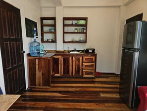 Una cucina con mobili in legno, un frigorifero in acciaio inossidabile e un dispenser d'acqua.