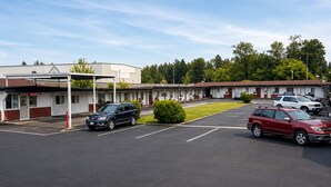 A motel with a parking lot, a covered area, and a row of rooms.