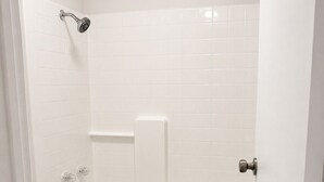 A bathroom with a toilet, a bathtub, and a shower head.
