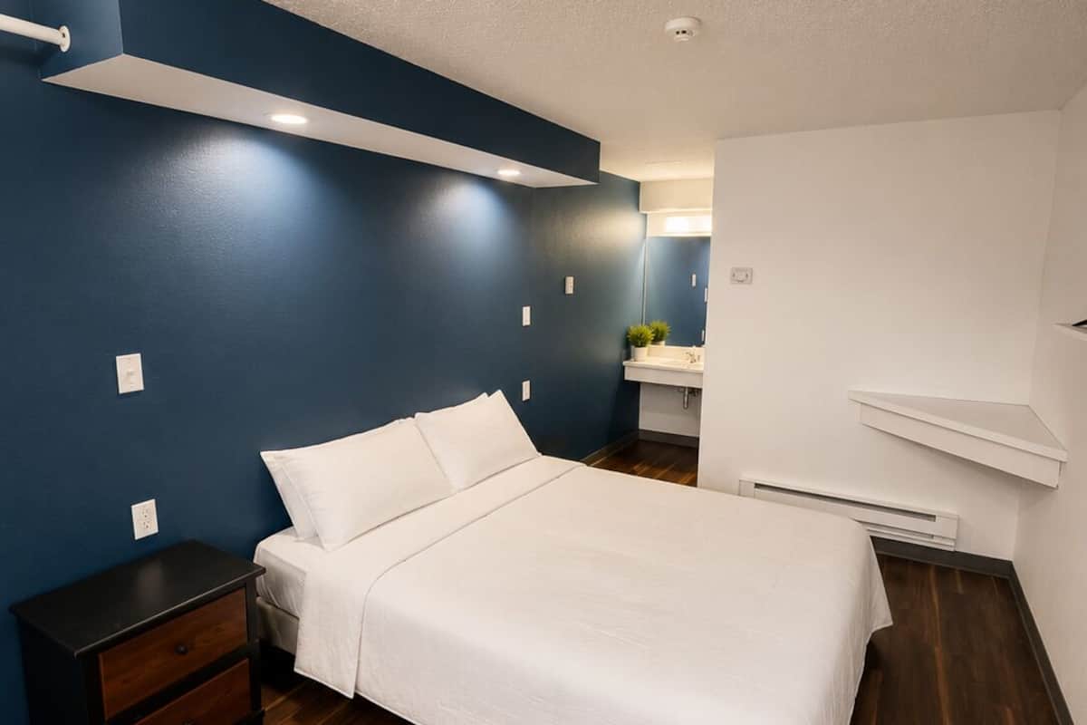 A bedroom with a bed, nightstand, and built-in shelf.