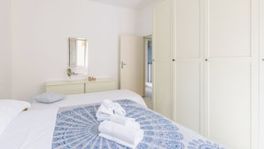 A bedroom with a bed, a bedside table with a mirror, a wardrobe, and a bathroom visible through an open door. - Apartment in Fano with 2 bedrooms sleeps 5 (Fano)