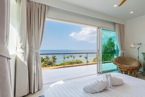 A bedroom with a large bed, a view of the ocean, and a balcony with a wicker chair. - SunTien, A Spectacular 4br Beach Front Pool Villa (Pha-ngan)