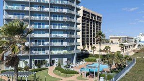 Un hotel de varios pisos con balcones, piscina y palmeras.