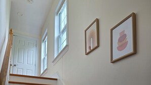 Un escalier avec des marches en bois et des murs blancs, menant à une porte située en haut.