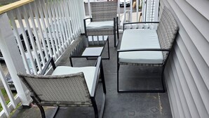Une terrasse extérieure couverte, dotée d’une rambarde, de deux chaises, d’une table et d’un banc.