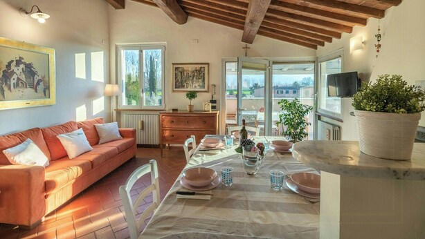 Un comedor con una mesa dispuesta para cuatro personas, un sofá y vistas al exterior.