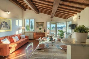 A dining area with a table set for four, a sofa, and a view of the outdoors. - Apartment with private pool near Lucca (Lucca)
