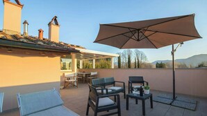 Una terraza con mesa, sillas, una tumbona y una sombrilla.