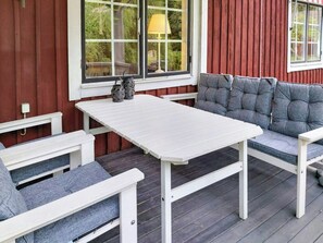 A covered outdoor seating area with a white table and grey cushioned benches. - Historic school in scenic Småland (Vetlanda)