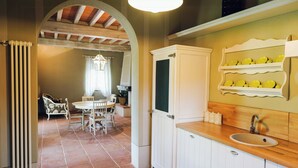 A kitchen with white cabinetry, a wooden countertop, and a shelf with yellow dishes. - Family apartment with pool in estate in Valdarno (Reggello)