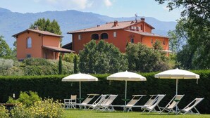 A villa with a garden, outdoor seating, and a mountain backdrop. - Family apartment with pool in estate in Valdarno (Reggello)