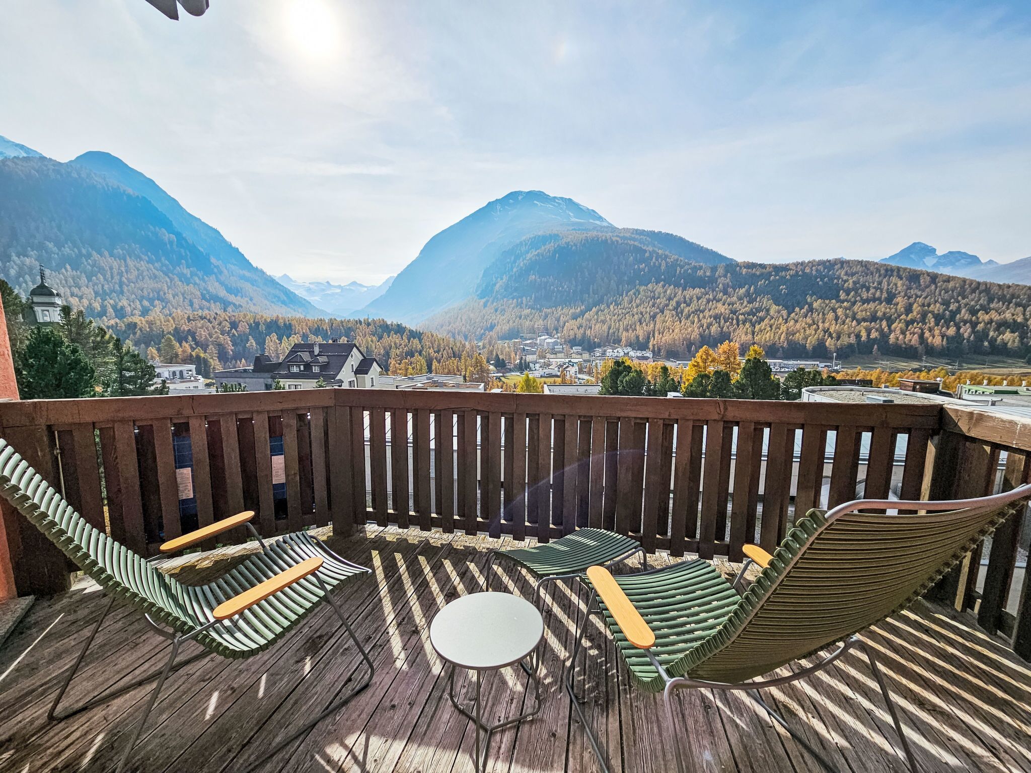 Une terrasse en bois offrant une vue sur les montagnes et une église.