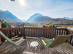 Eine Holzterrasse mit Blick auf Berge und eine Kirche.
