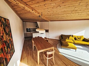 Ein modernes Interieur mit einem Holztisch, einer Couch und einer Küchenzeile.