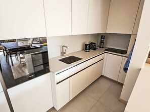 Eine moderne Küche mit weißen Schränken, einer schwarzen Arbeitsplatte, einer Spüle und einer Kaffeemaschine.