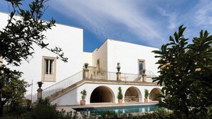 Ein weißes Gebäude mit Pool, Bogenfenstern und einem Balkon.