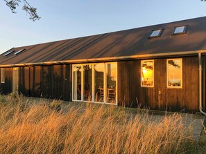 Un bâtiment moderne doté d’un toit en pente, de grandes portes-fenêtres coulissantes et d’une petite fenêtre.