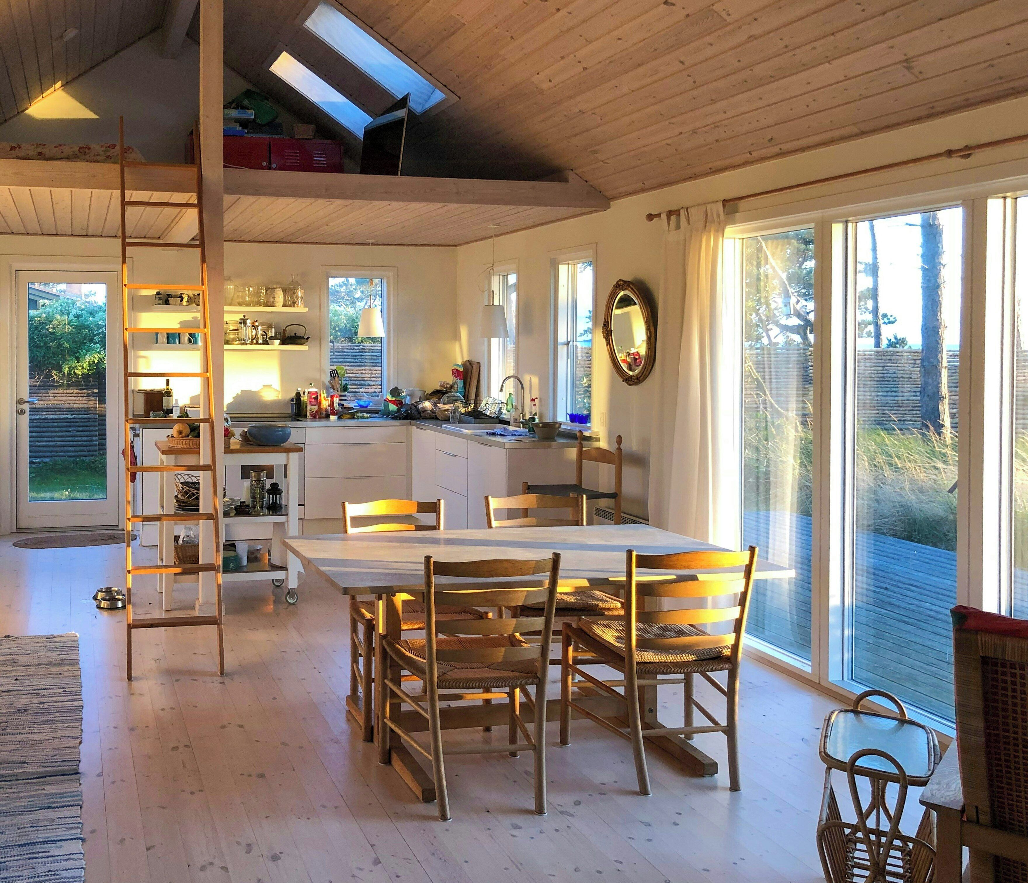 Une cuisine spacieuse avec un coin repas, un plancher en bois et de grandes fenêtres.
