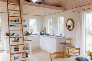 Une cuisine avec des armoires blanches, une échelle en bois, un évier et un miroir.
