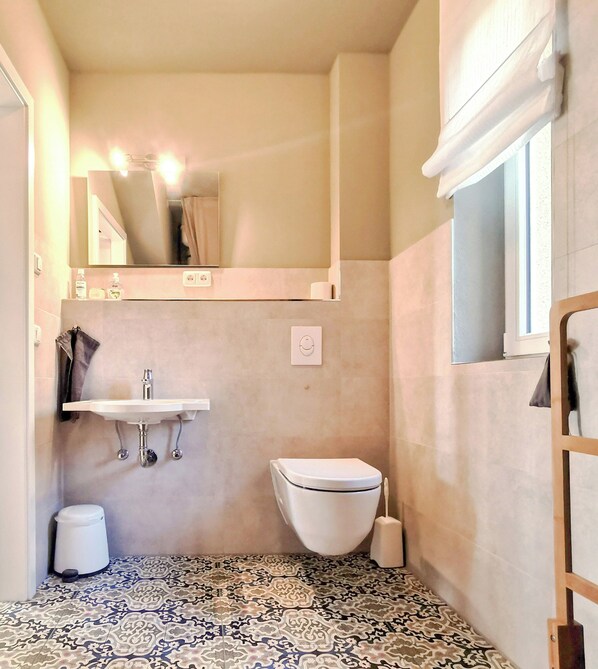 A bathroom with a sink, toilet, and mirror.