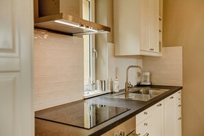 A modern kitchen with a black countertop, stainless steel sink, and white cabinets.