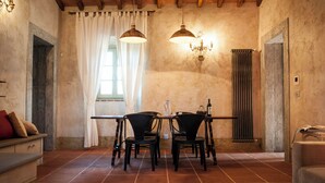 Uma sala de jantar com uma mesa, cadeiras, um jarro, uma garrafa e um livro.