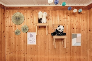 Una stanza in legno con un peluche a forma di panda, mobili in legno e lanterne decorative in carta.
