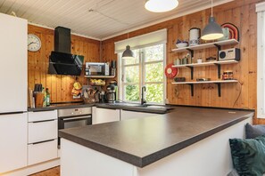 Una cocina moderna con paredes de madera, una isla grande, un microondas y un reloj.