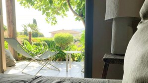 A bedroom with a bed, a chair, a lamp, and a view of a garden. - Villa with sea view and garden in Corsica (Porto-Vecchio)