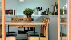 A modern kitchen with a dining table, chairs, pendant lights, and a potted plant. - Cozy summer house in Agger near the North Sea (Vestervig)