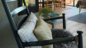 A modern living room with a sofa, a dining area with wooden chairs, and a large sliding glass door leading to an outdoor patio. - Cozy summer house in Agger near the North Sea (Vestervig)