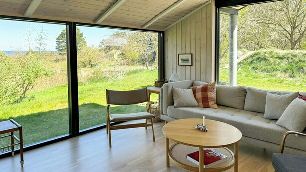 Een moderne woonkamer met een houten vloer, een ronde salontafel, een bank en een fauteuil.