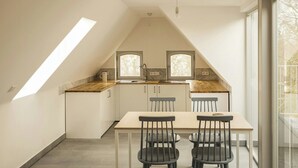 Et moderne køkken med spiseplads, komplet med ovenlys, store vinduer og udsigt til det fri.