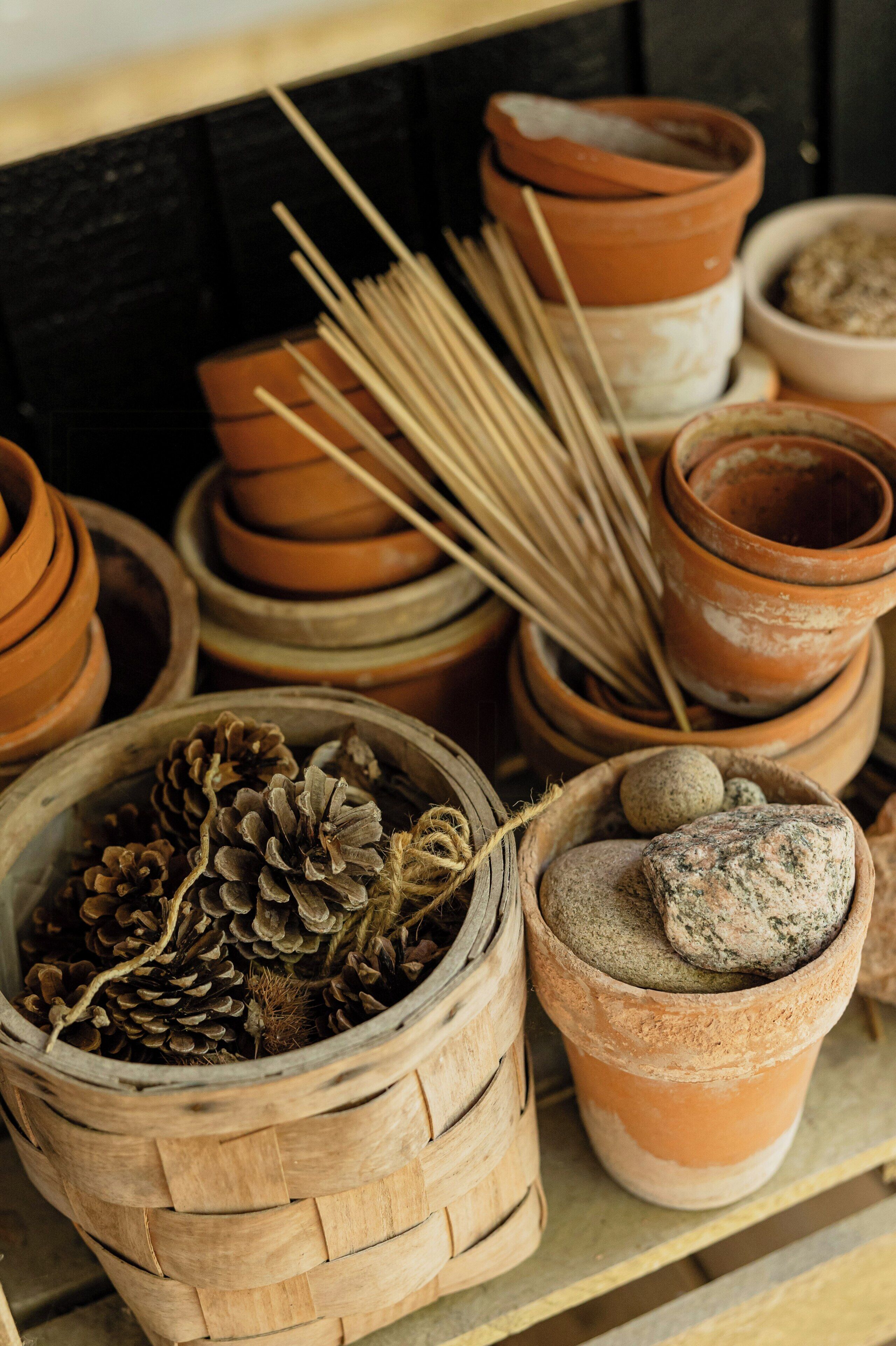 Terracotta pots, a woven basket with pinecones, and a bowl with stones.