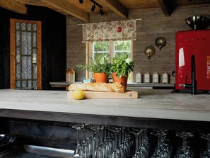 A kitchen with a wooden countertop, a red appliance, and a window with a floral valance. - Country life near city and lake with room for many (Torestorp)