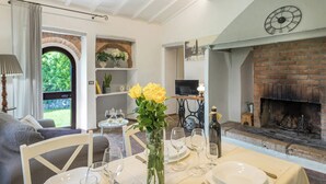 Een eethoek met een tafel voor vier personen, een open haard en een televisie op de achtergrond.