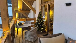 A wooden deck with wicker furniture, a Christmas tree, and a glass door leading inside. - Luxury penthouse with Mont Blanc views in Megève (Megève)