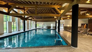 An indoor swimming pool with wooden beams, large windows, and lounge chairs. - Luxury penthouse with Mont Blanc views in Megève (Megève)
