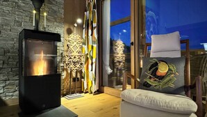 A cozy room with a fireplace, decorative wall panels, a wicker chair, and a cushion with a fruit design. - Luxury penthouse with Mont Blanc views in Megève (Megève)